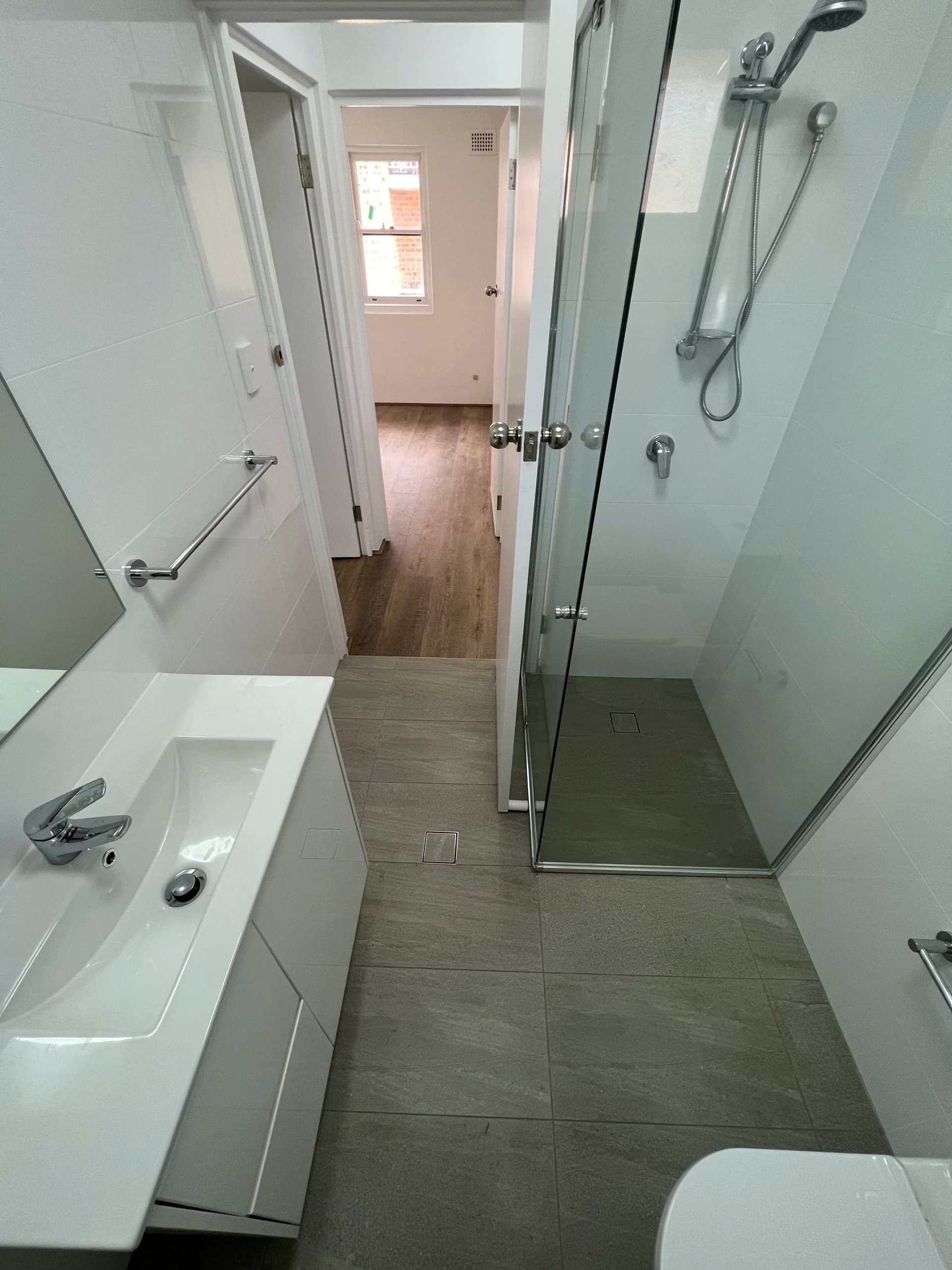 Renovated Artarmon apartment bathroom with white wall tiles and a frameless glass shower screen