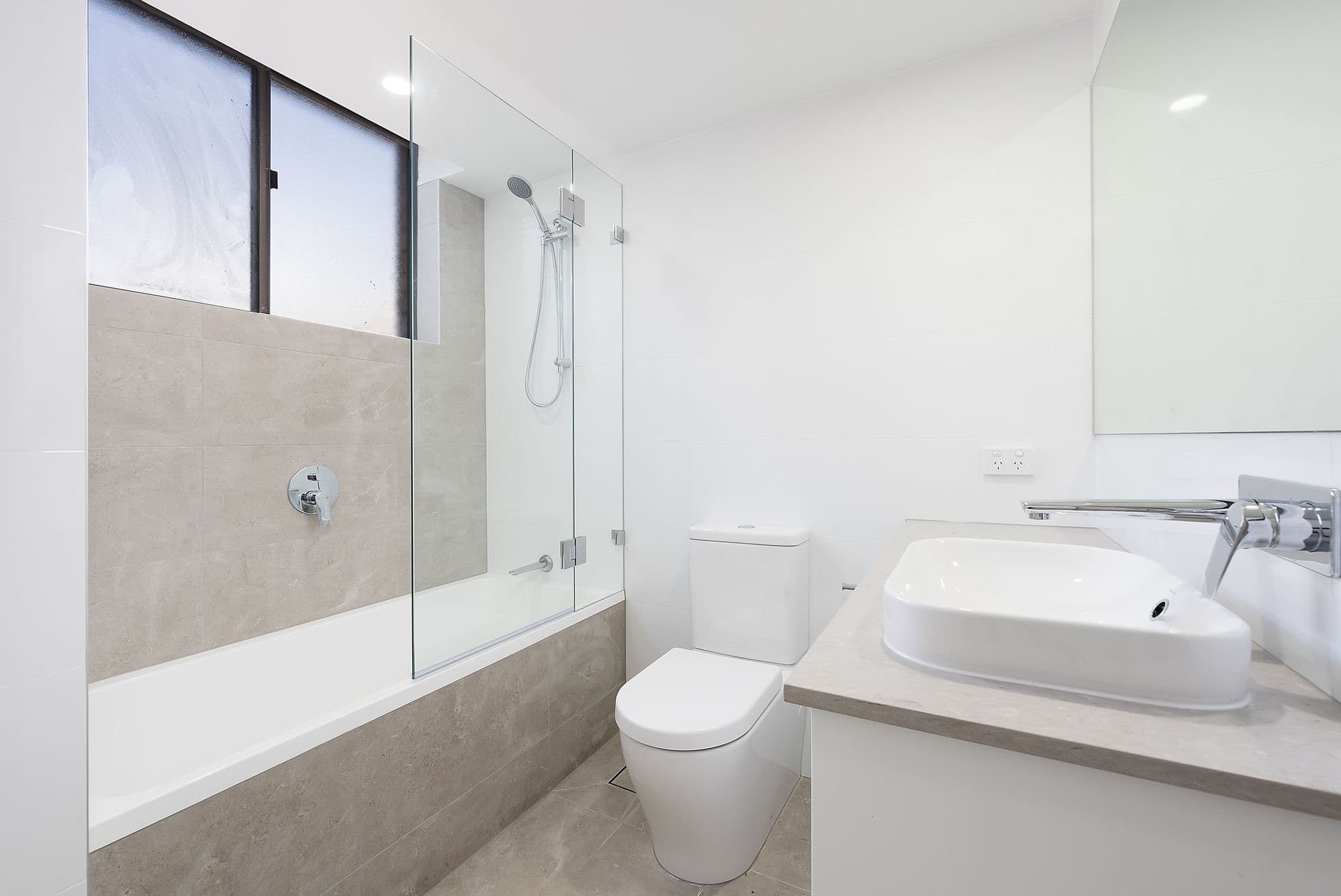 Second bathroom in the Market Street CBD apartment with a built-in bath and beige tiling