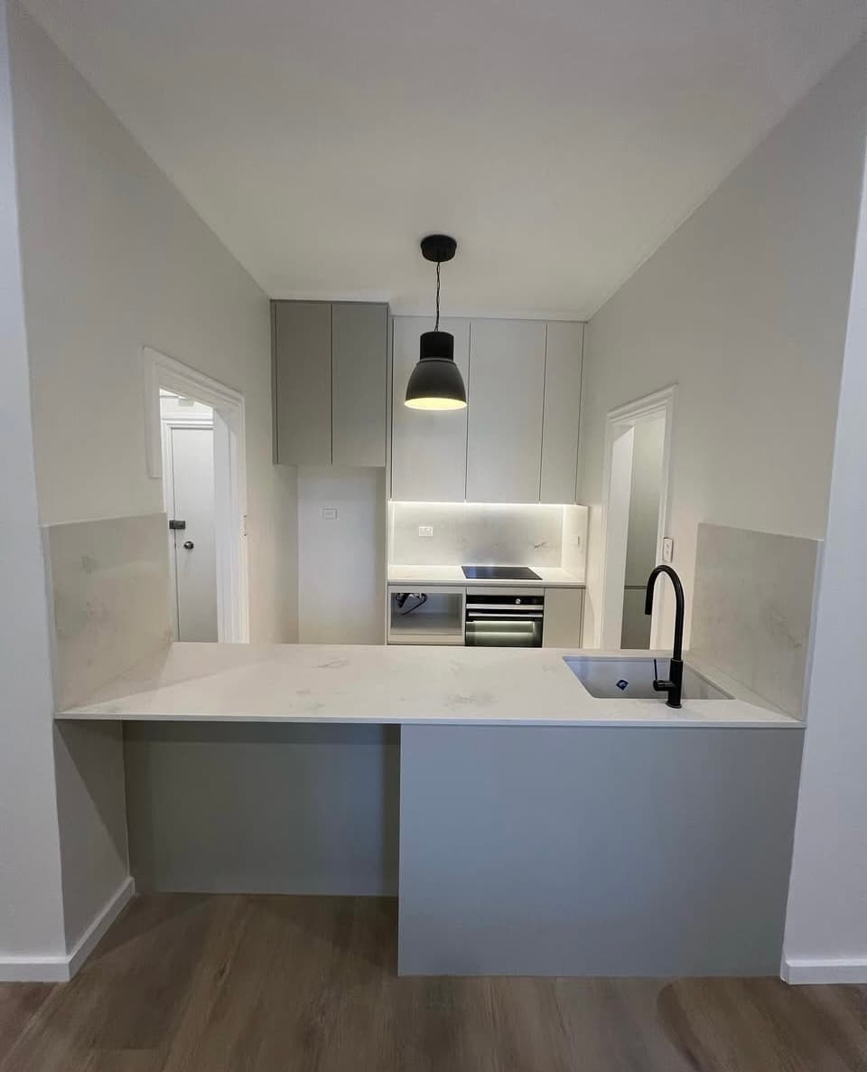 Surry Hills apartment kitchen with a stone peninsula benchtop and grey handleless cabinetry