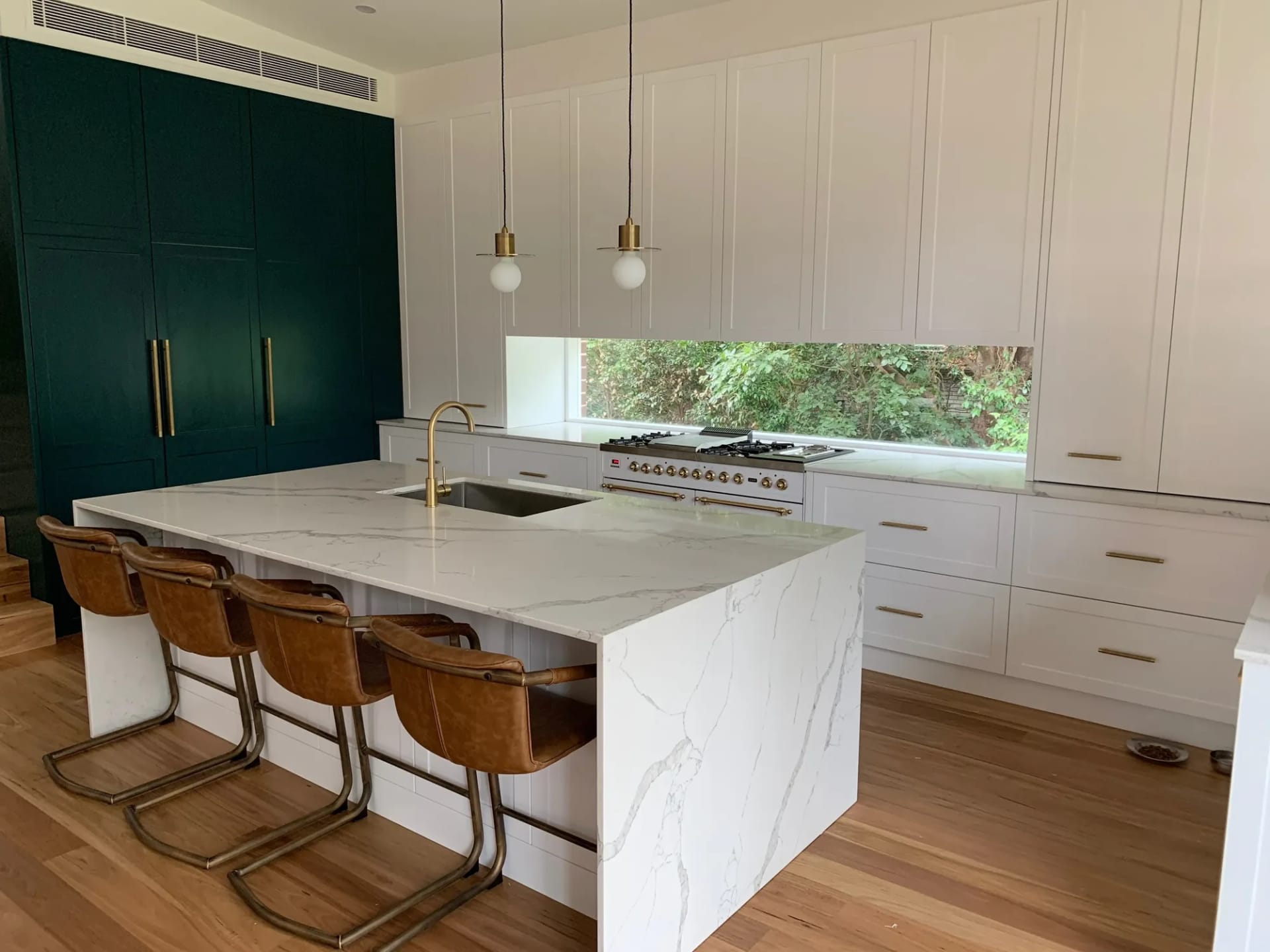 Apartment kitchen with green cabinetry and marble island