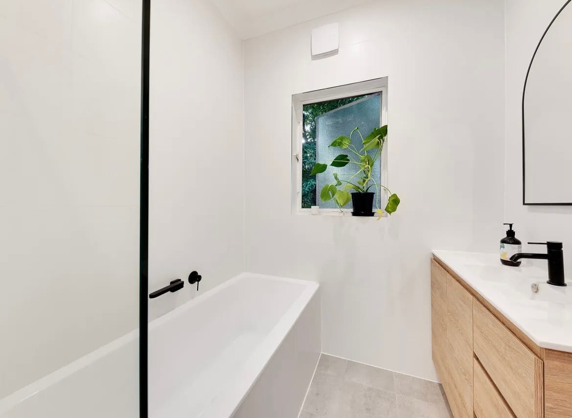Renovated apartment bathroom with bathtub and arched mirror