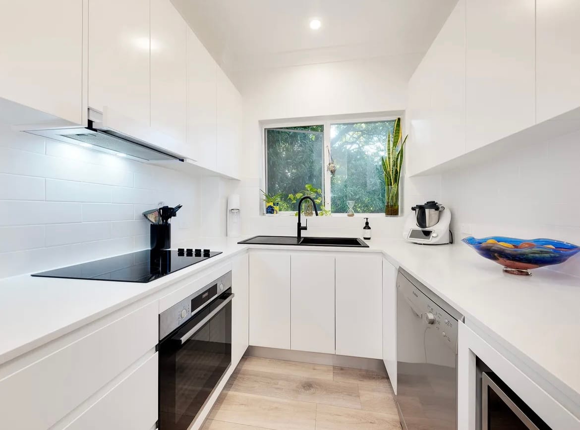 Bright white U-shaped apartment kitchen in Lane Cove