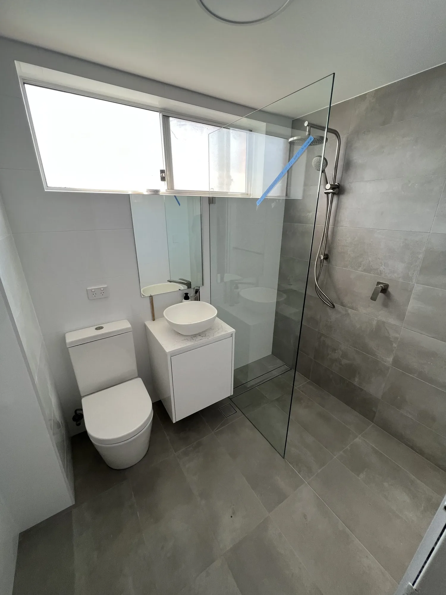 Renovated Stanmore apartment bathroom with round mirror and timber vanity