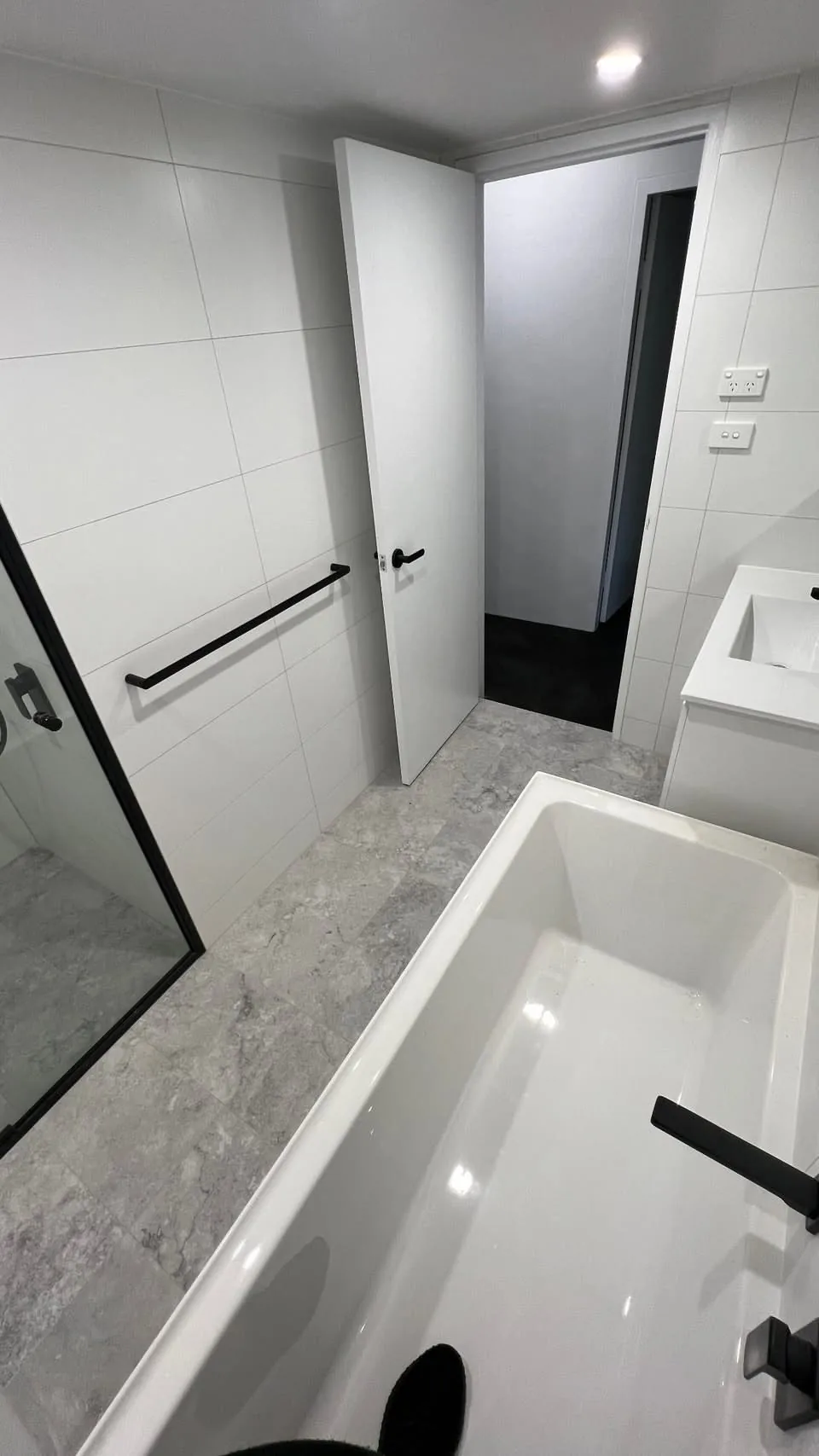 Bathroom entry showing terrazzo floor and black fixtures