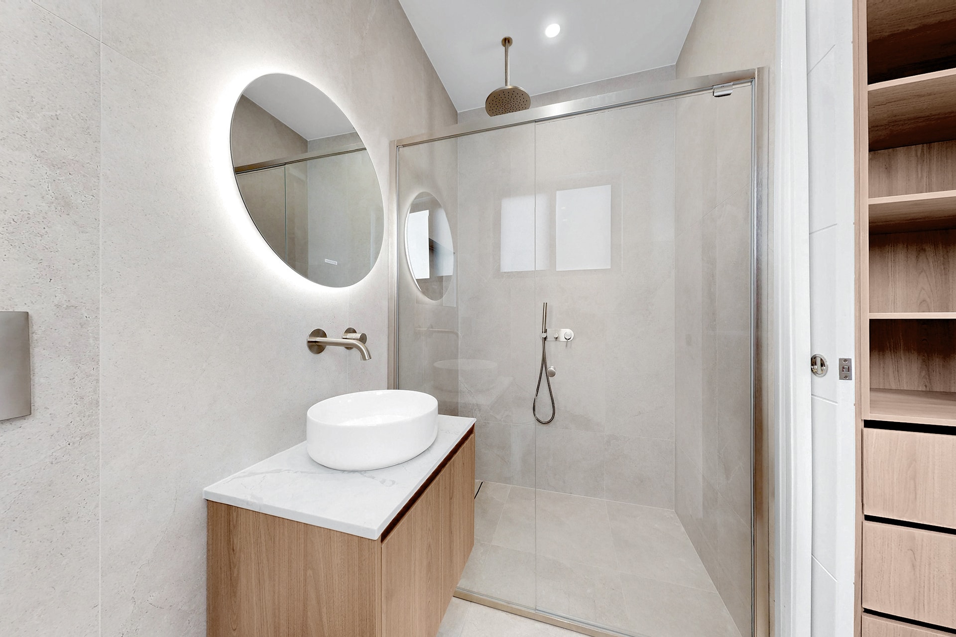 Modern apartment ensuite with circular mirror and elegant fixtures