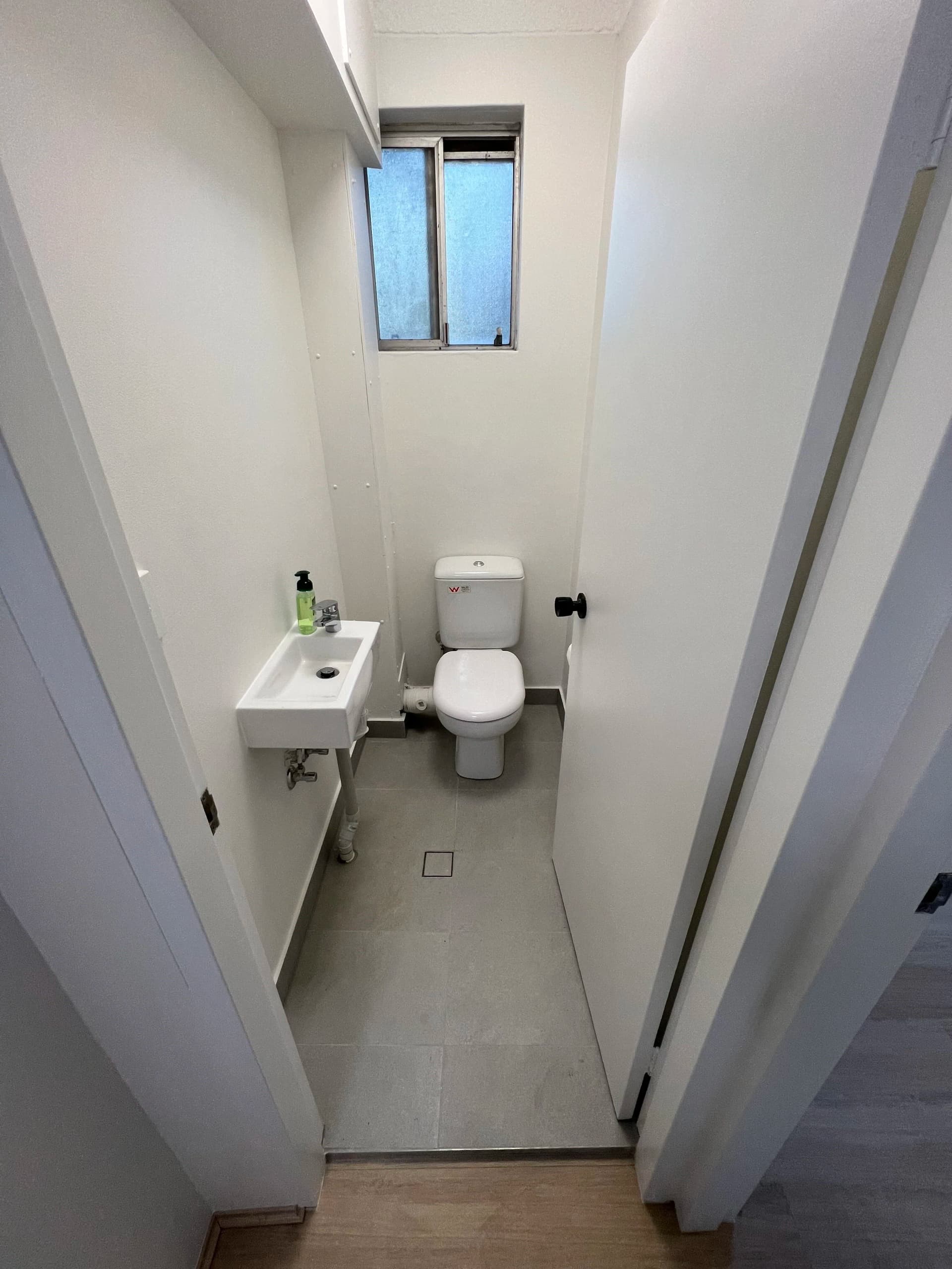 Compact renovated powder room with grey floor tiles and a wall-hung basin