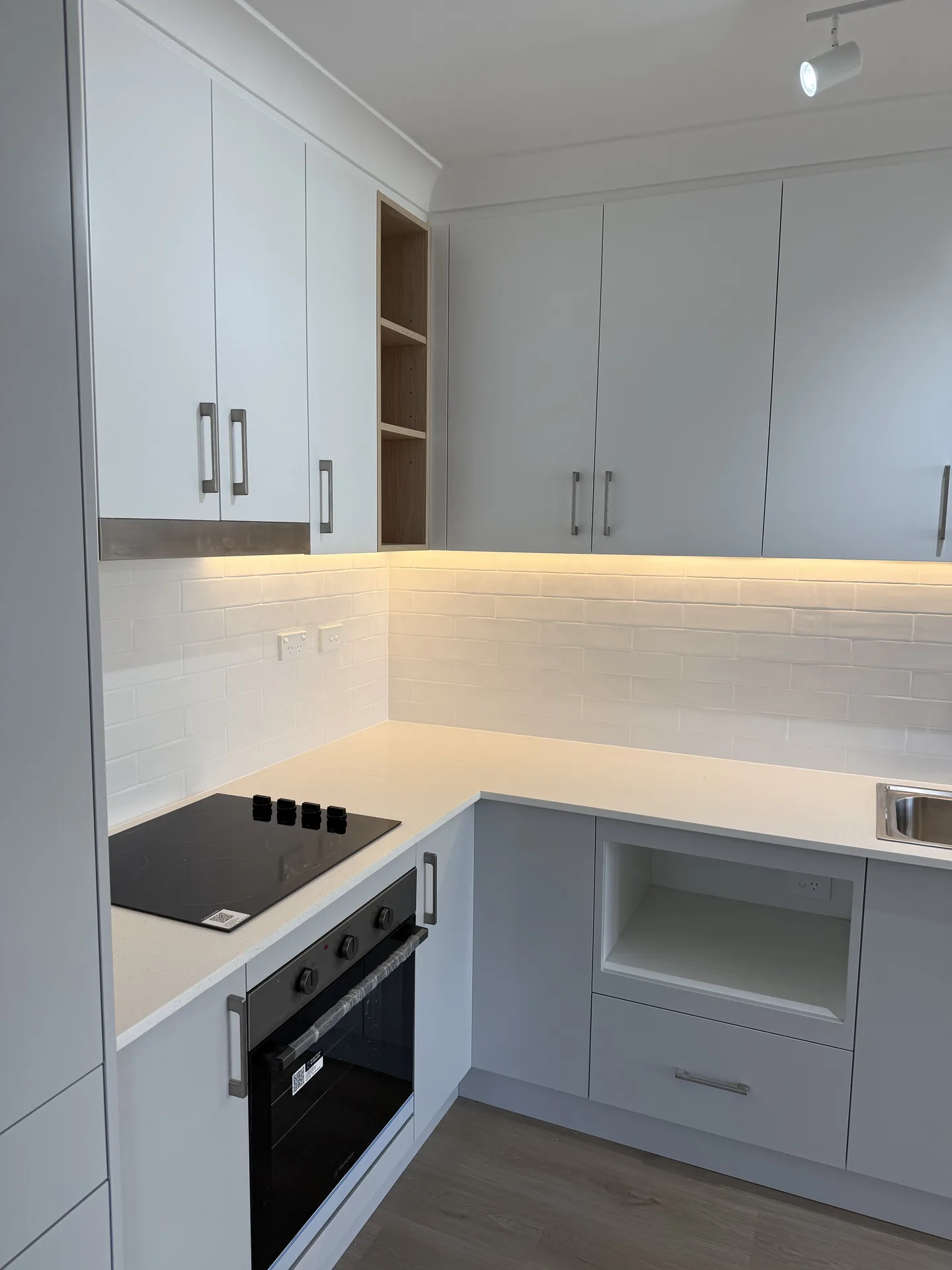Corner overhead cupboards with warm strip lighting and open timber-look shelves
