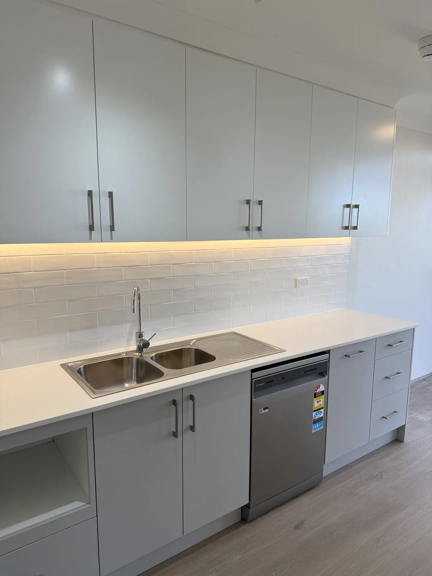Long sink run with dishwasher, drawer bank and overhead cupboards lit from below