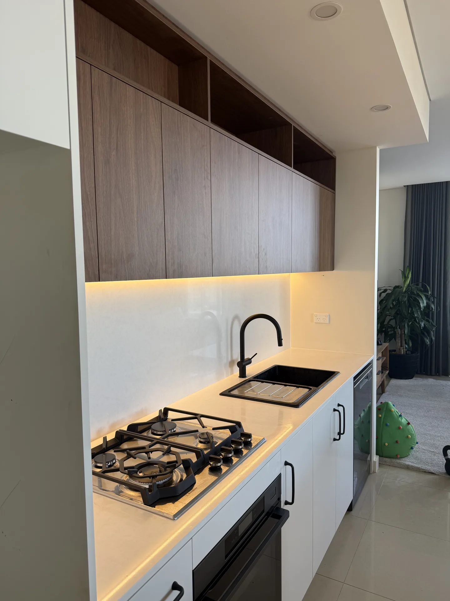 Warm LED strip under the overhead cabinets lighting the benchtop and splashback