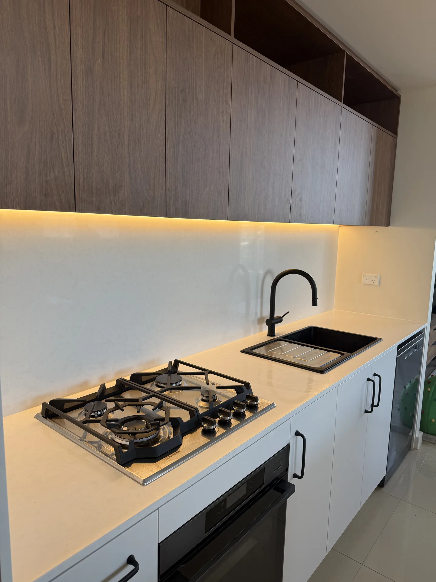 Stone-look benchtop with gas cooktop, black composite sink and black gooseneck mixer