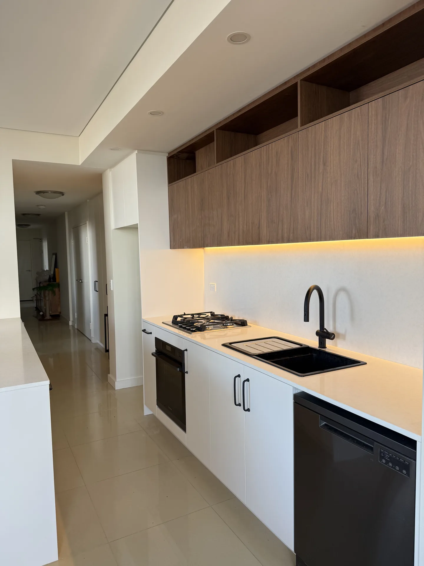 Apartment kitchen with white base cabinets, timber-look overheads and a white island
