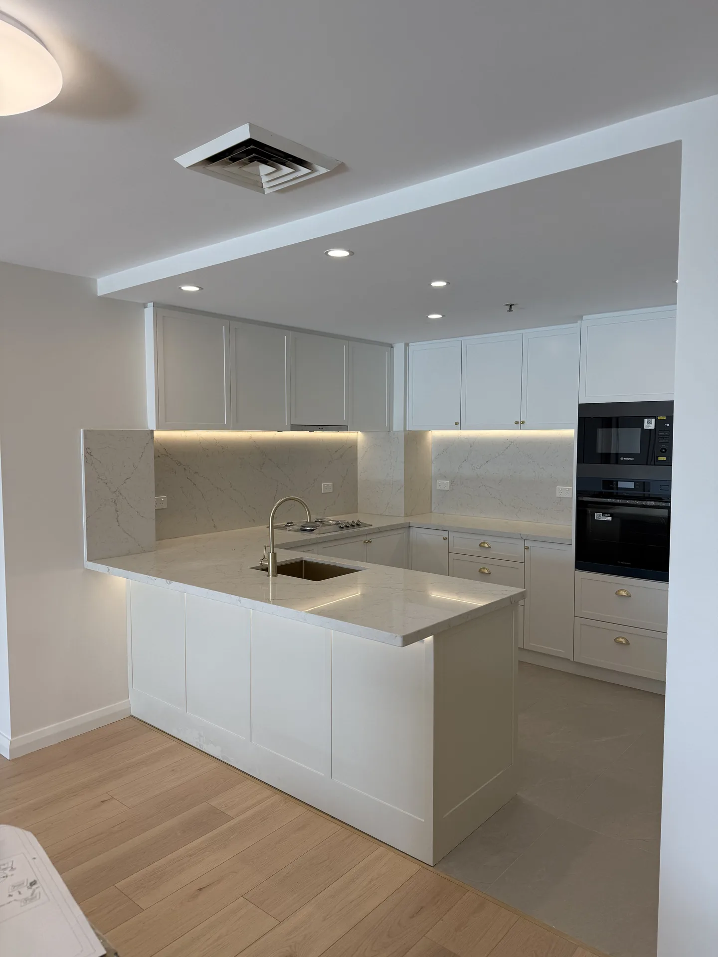 Renovated U-shaped kitchen with white shaker doors, stone peninsula and oak-look floorboards