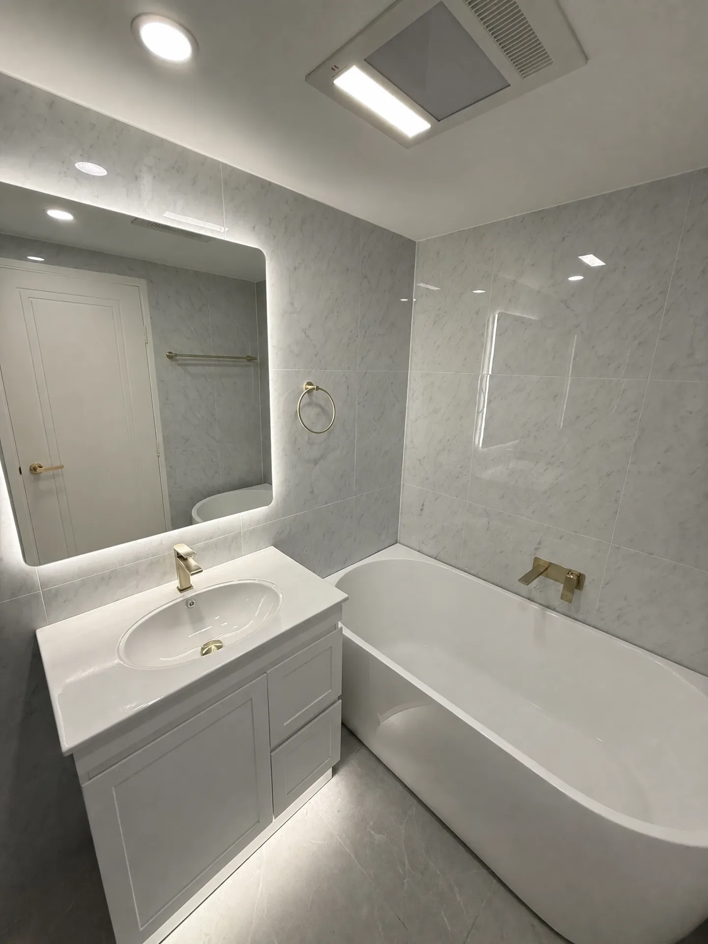 Second bathroom with marble-look tiles, a built-in bath and a wall-mounted brass spout