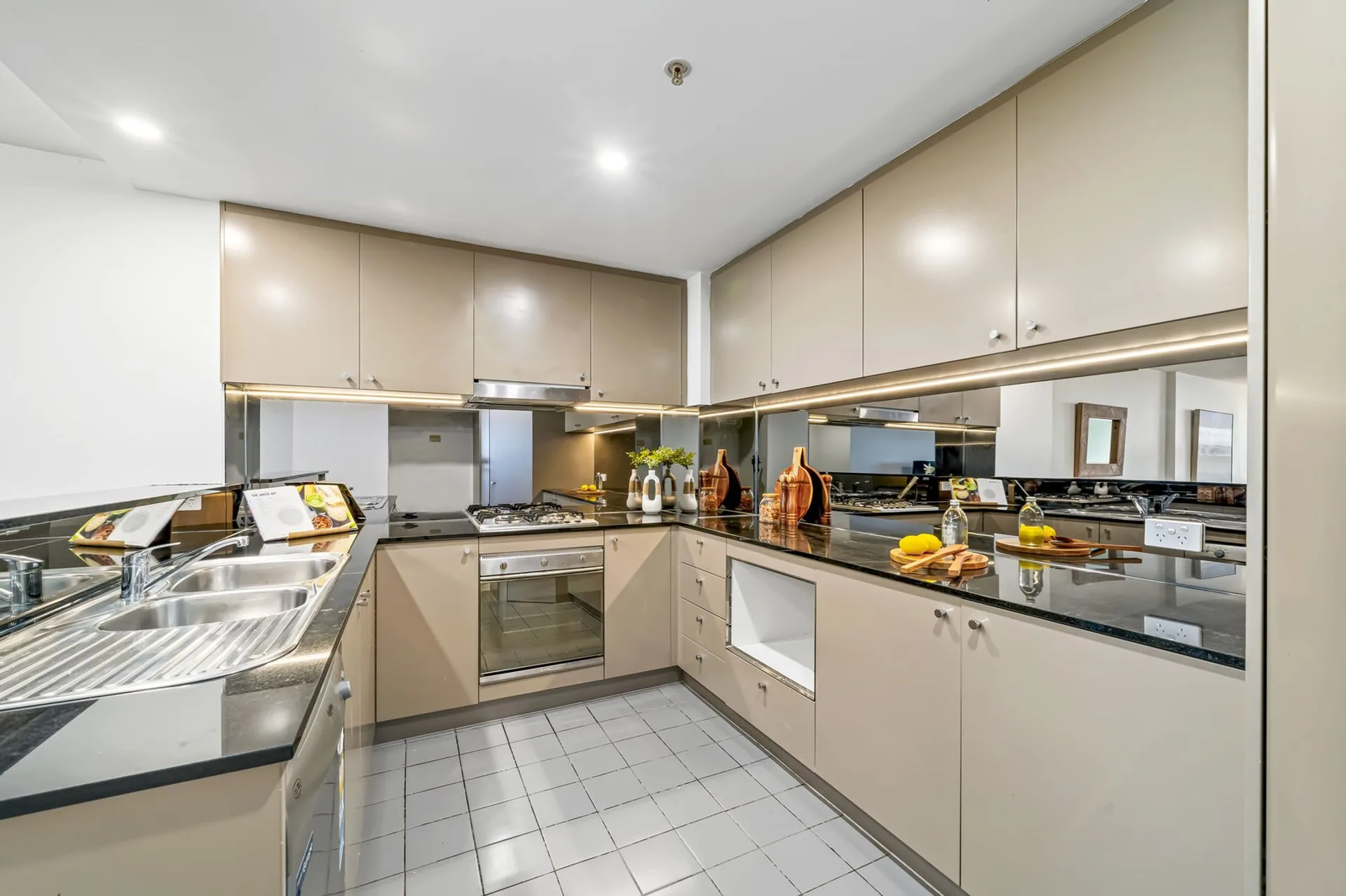 Original kitchen with beige gloss laminate doors, dark granite benchtops and a mirror splashback