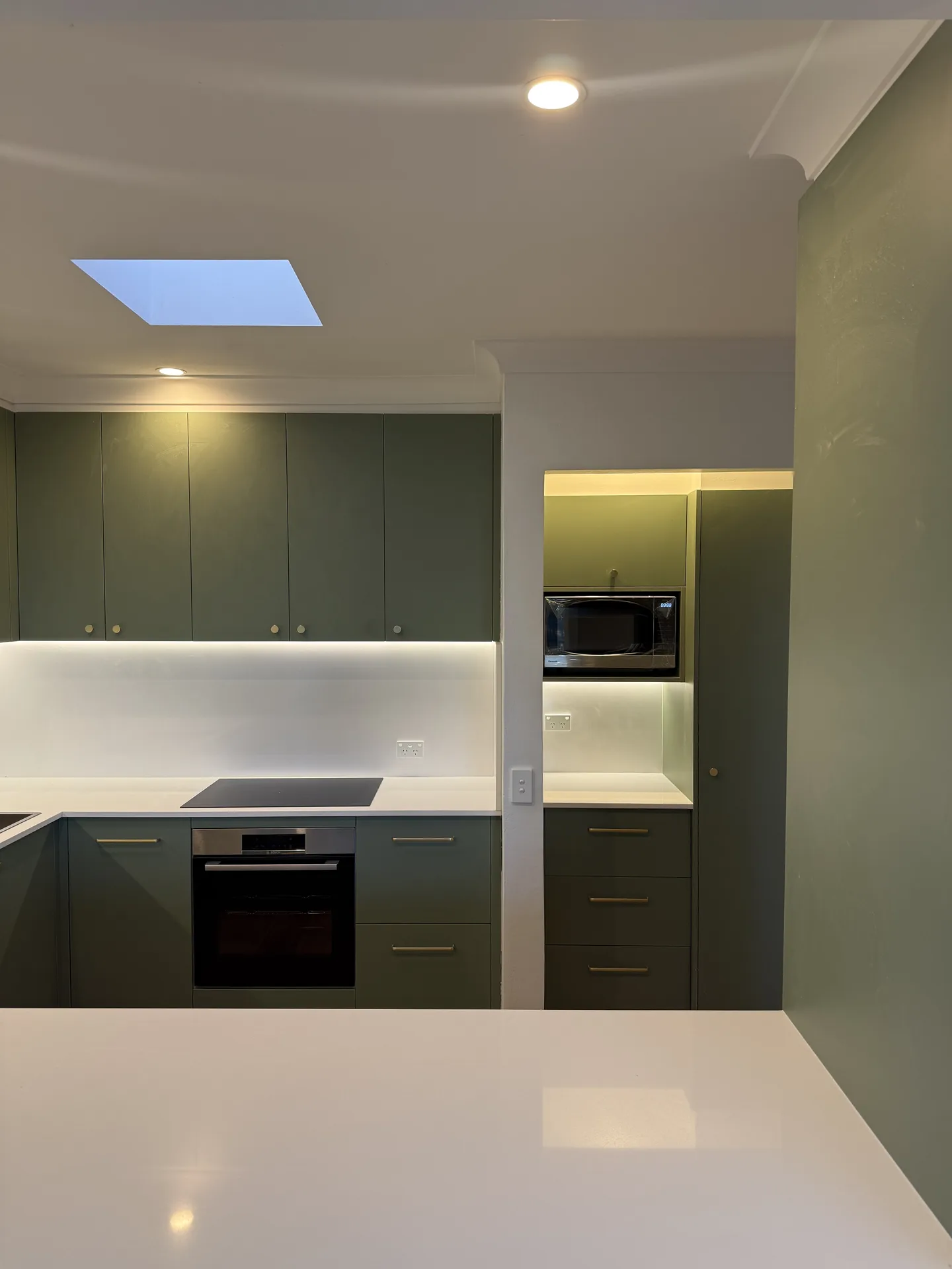 Olive kitchen joinery with a built-in microwave nook and bench beneath it
