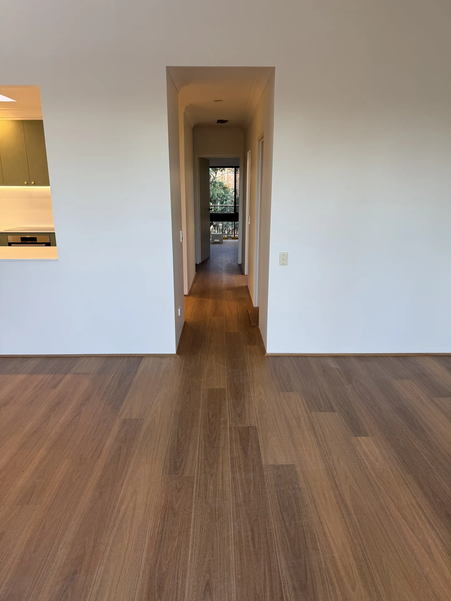 Timber-look flooring running from a renovated living room down the hall of a Drummoyne apartment