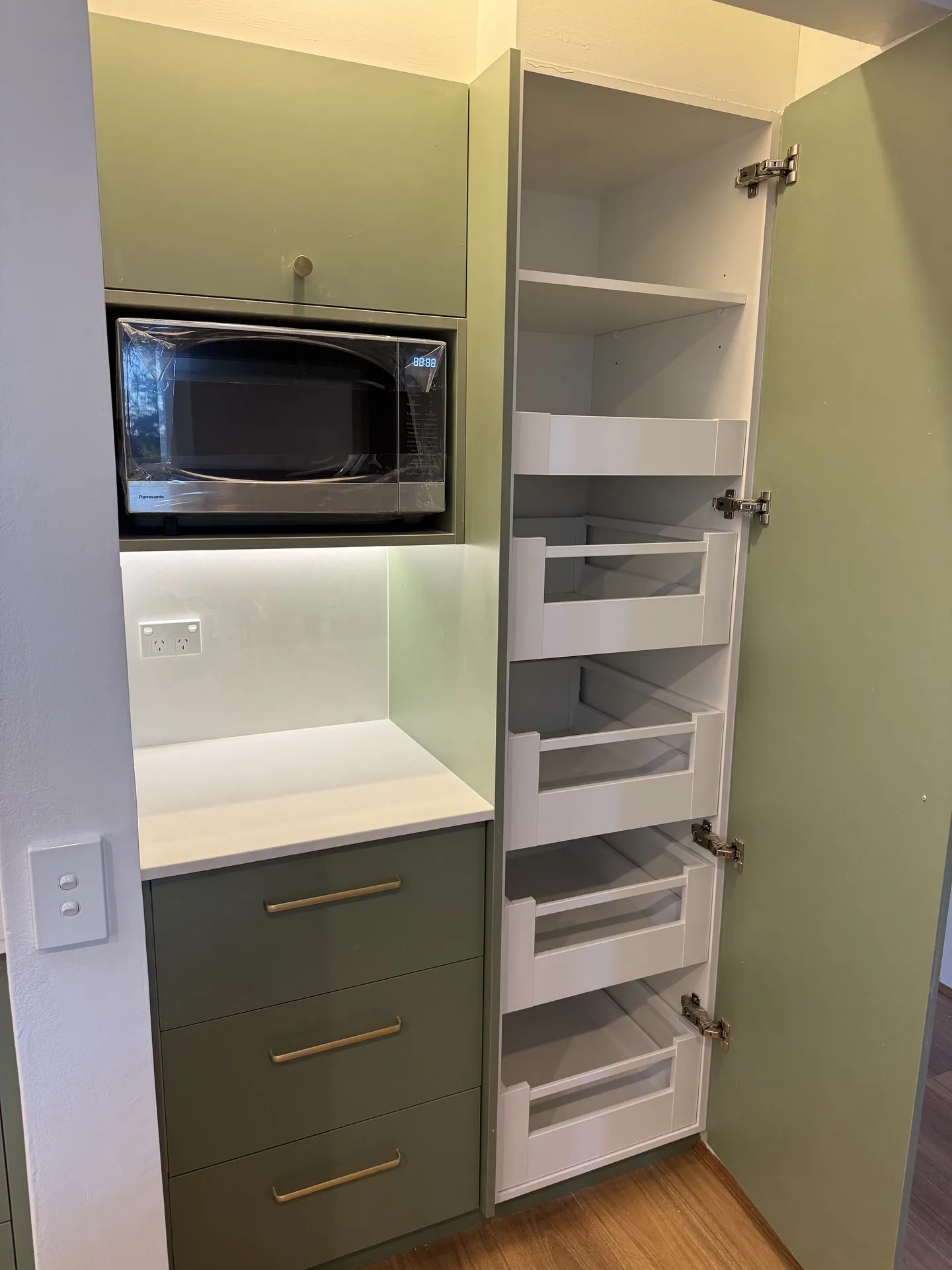 Tall pantry cupboard open to show four white inner pull-out drawers