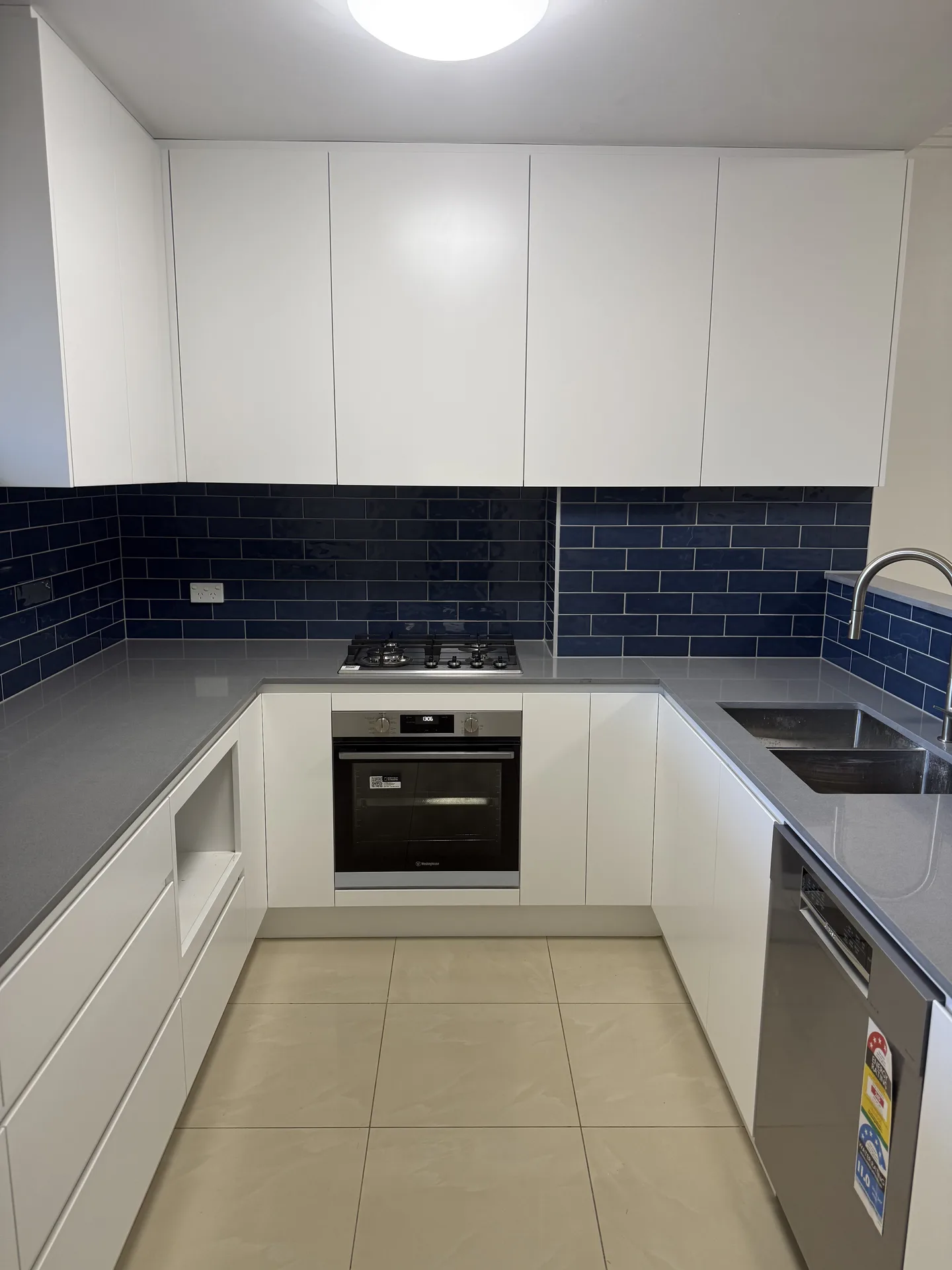 U-shaped North Strathfield apartment kitchen with white cabinetry and blue subway tiles