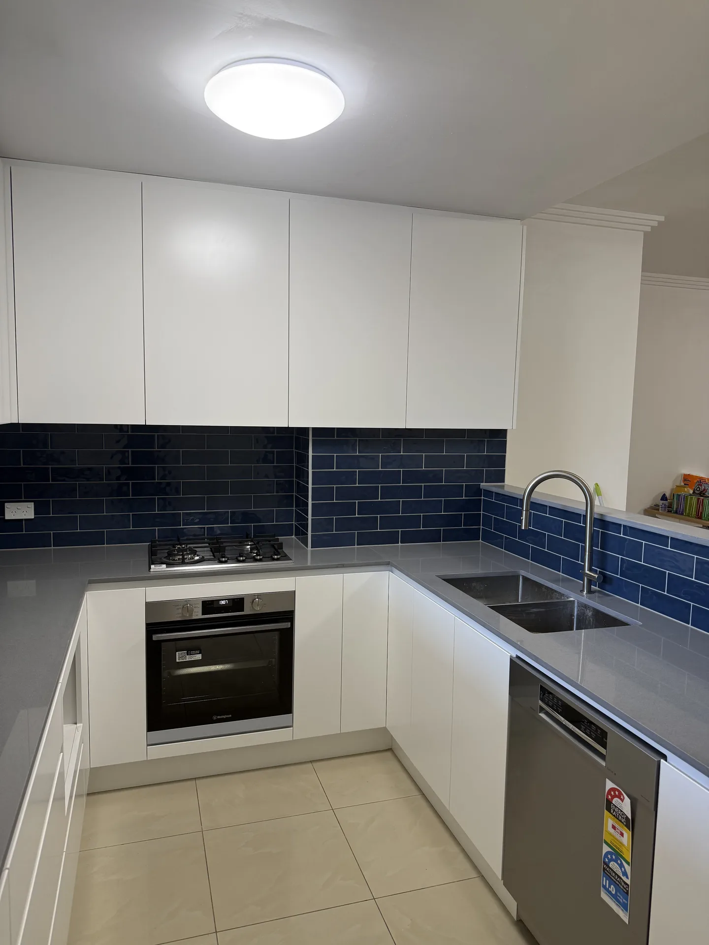Renovated North Strathfield apartment kitchen with navy subway tile splashback and grey stone benchtop