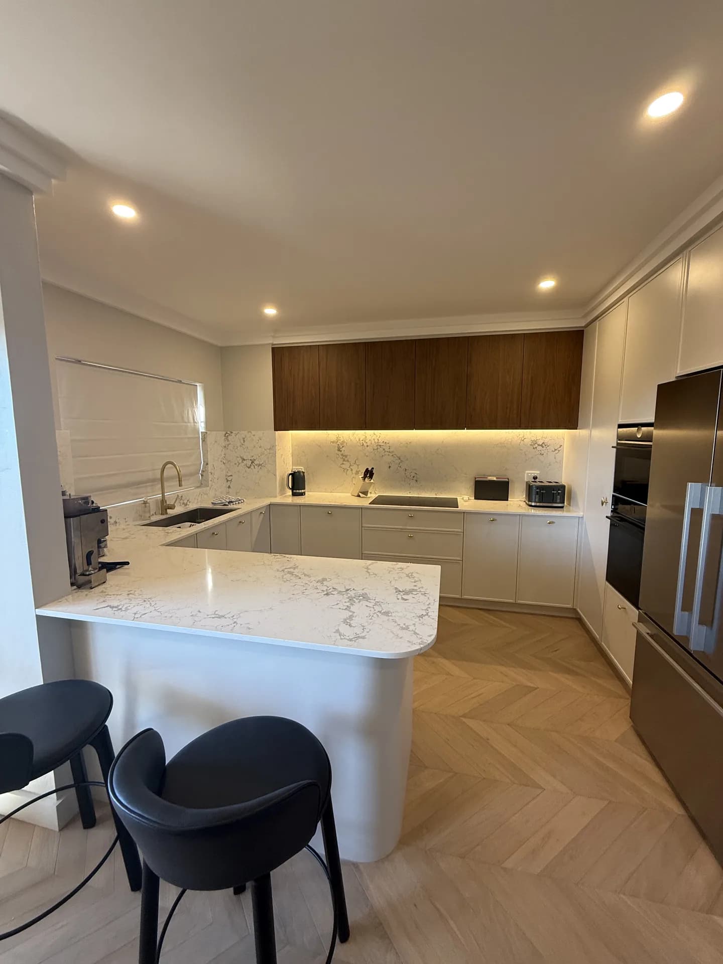 Renovated kitchen with marble-look stone benchtops, walnut-look overheads and chevron flooring