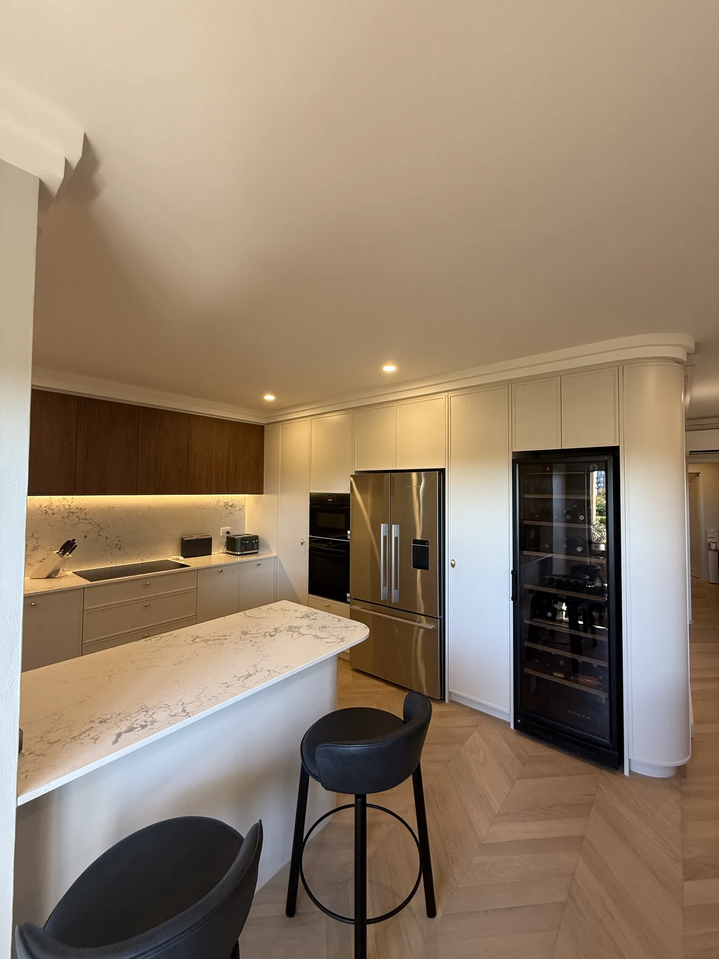 The same North Sydney kitchen after renovation, with a curved stone peninsula and floor-to-ceiling joinery