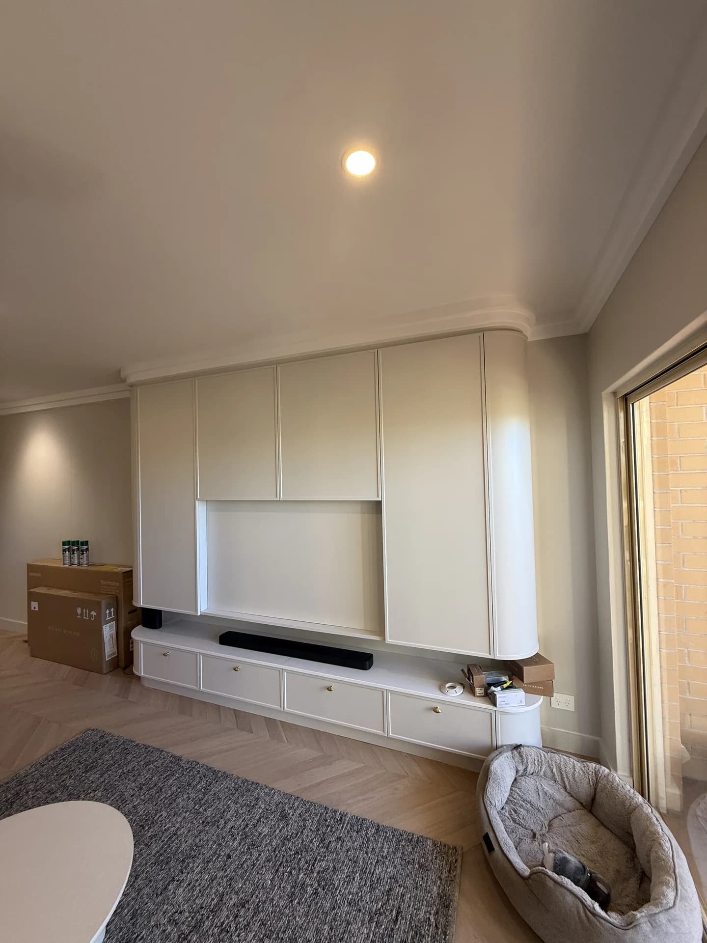 Floor-to-ceiling apartment joinery with integrated appliances and a curved return