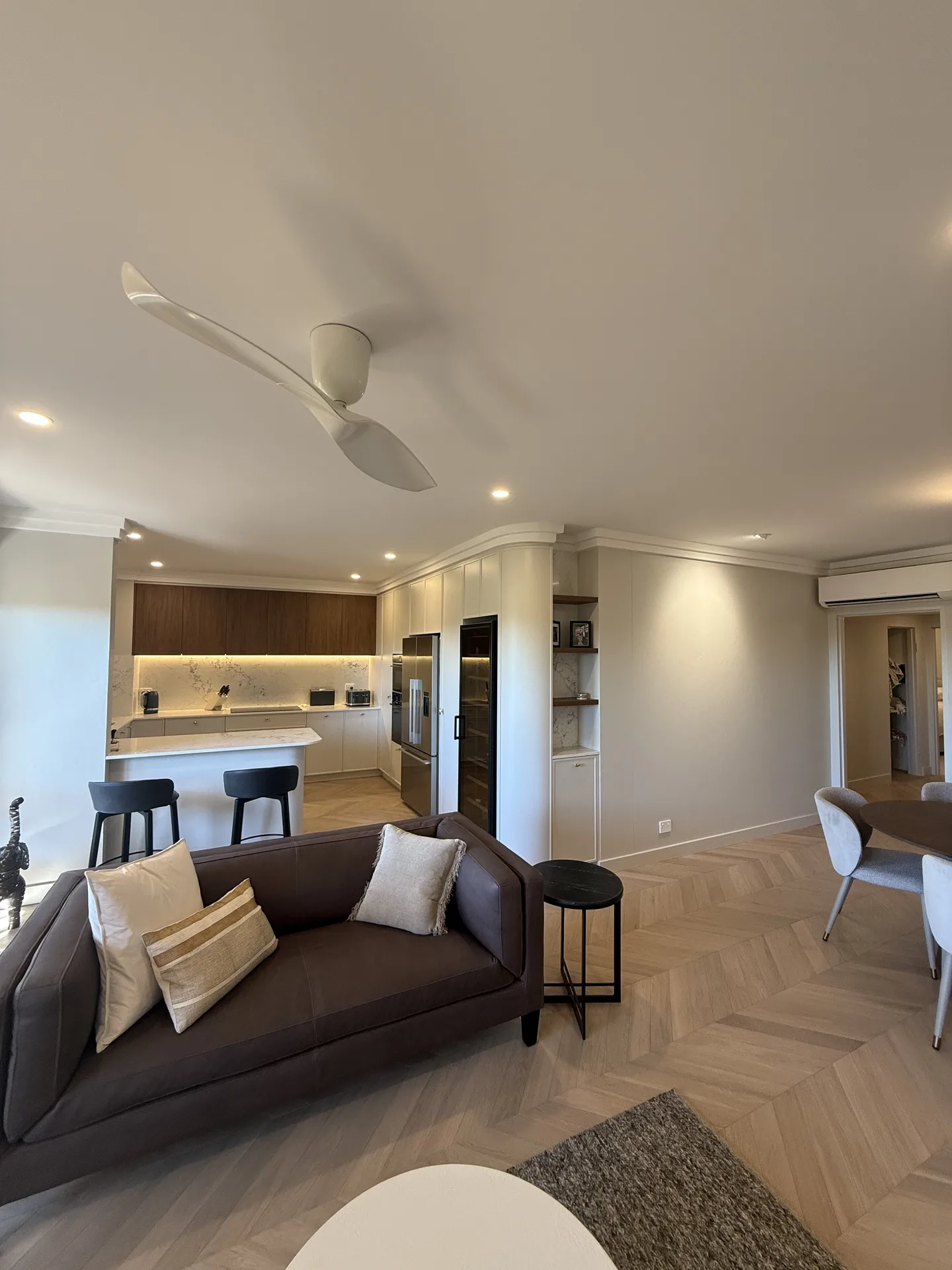 Open-plan living area looking across a leather sofa to the kitchen peninsula