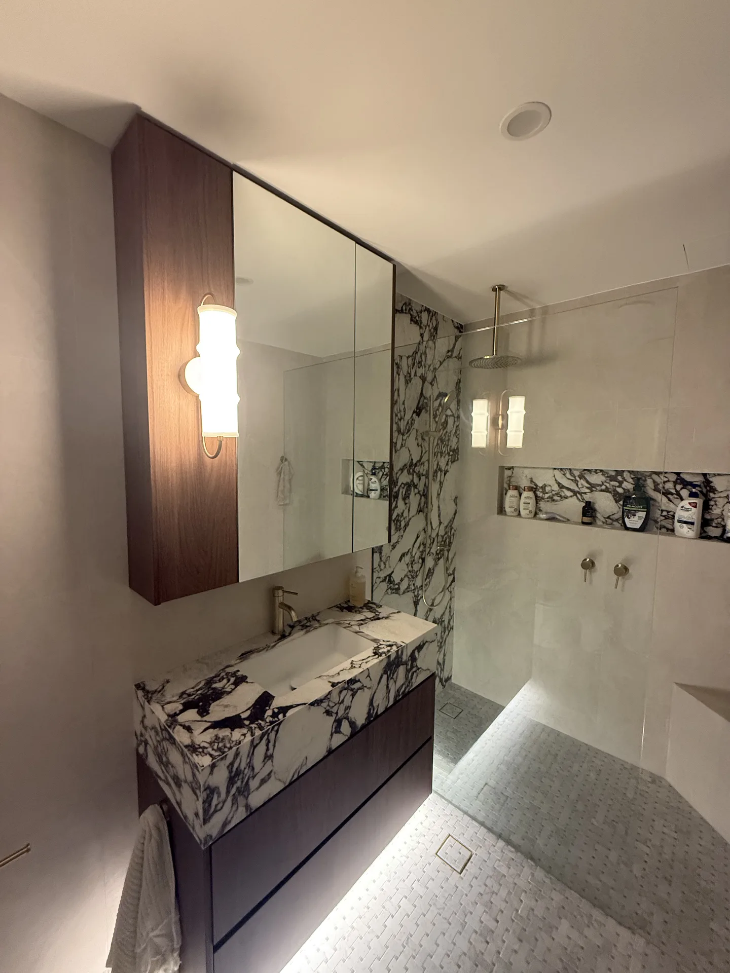 Ensuite from the doorway showing mirrored cabinet, fluted glass sconce and marble niche