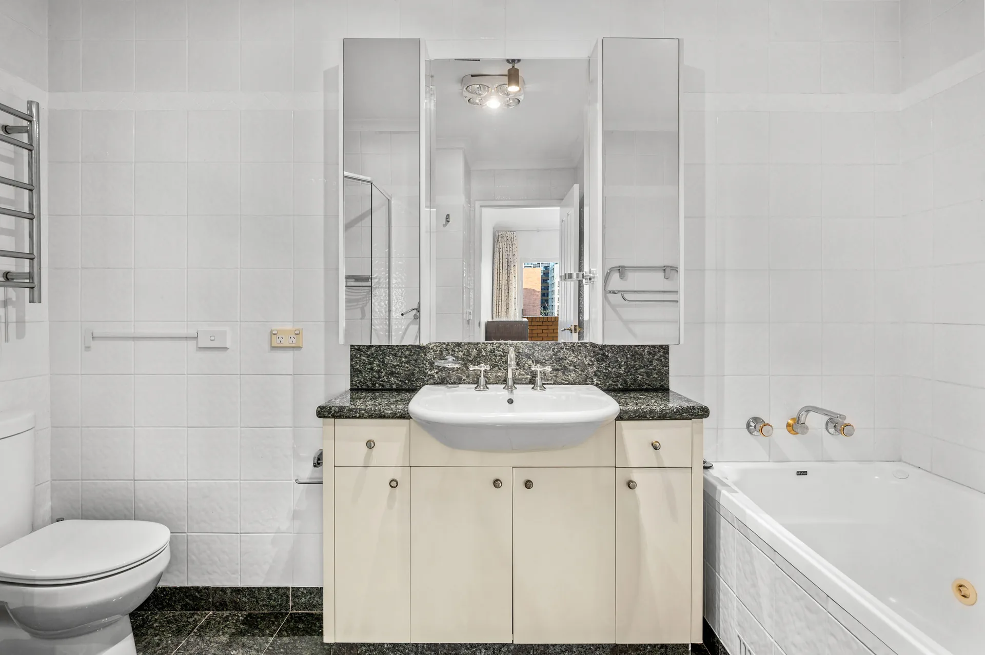 Original North Sydney apartment bathroom with white square wall tiles and a cream vanity with a green granite top