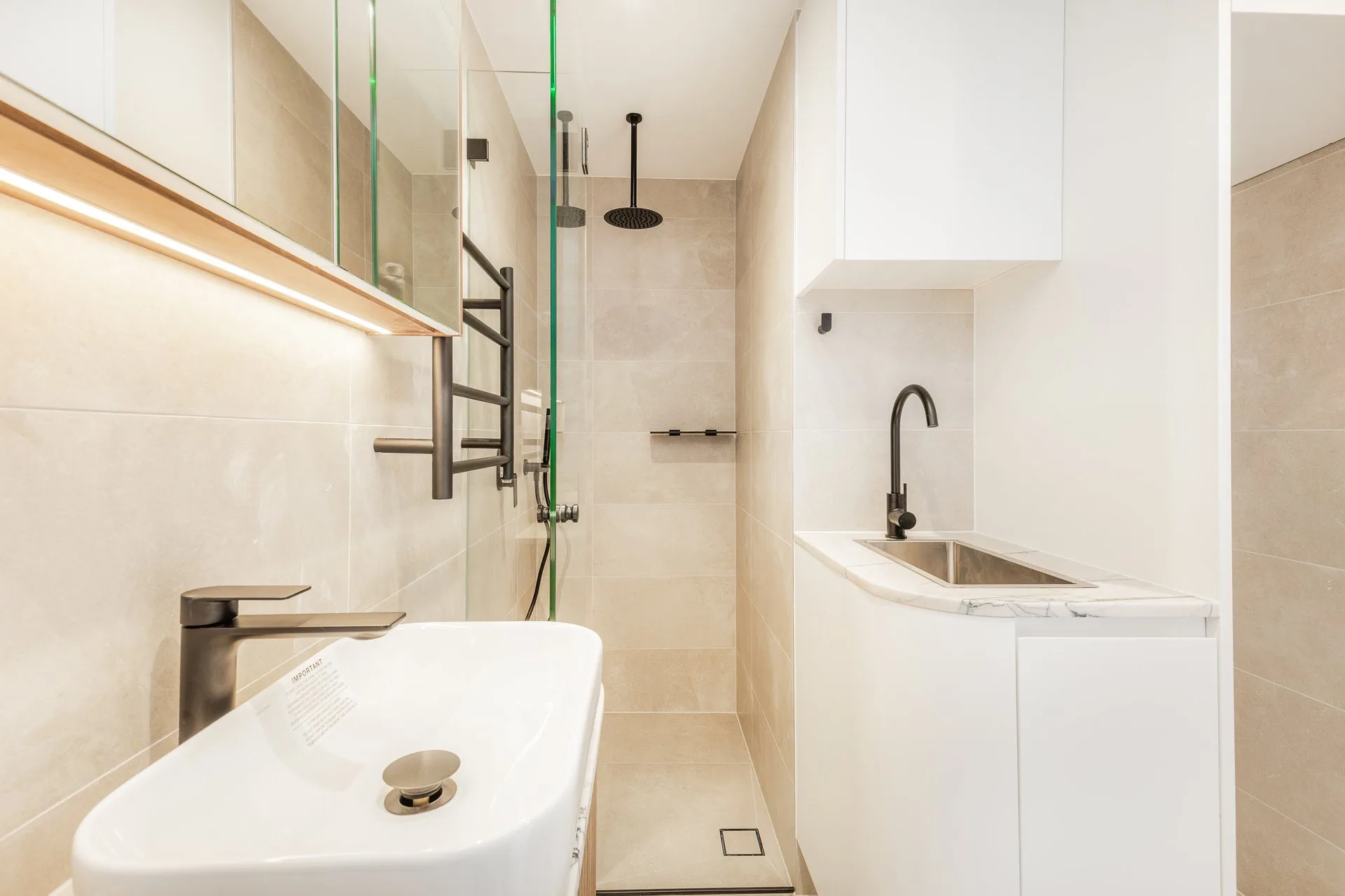 Frameless glass shower with a black rain head, tiled niche and a black heated towel rail