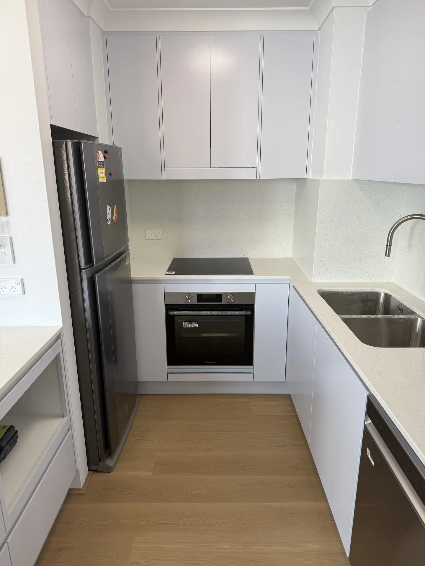 Flush cooktop above an under-bench oven with stone splashback behind