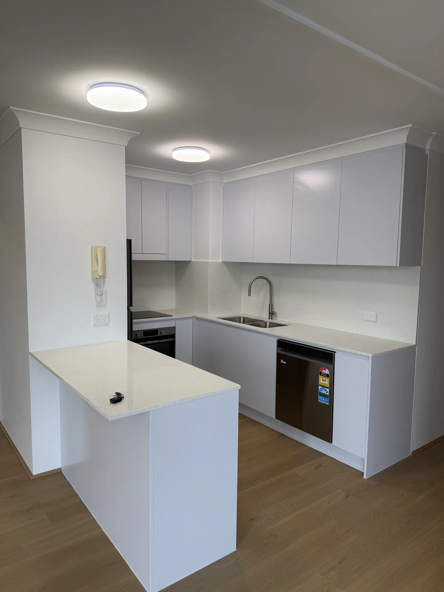 Kitchen seen from the living side, overhead cupboards running to the cornice
