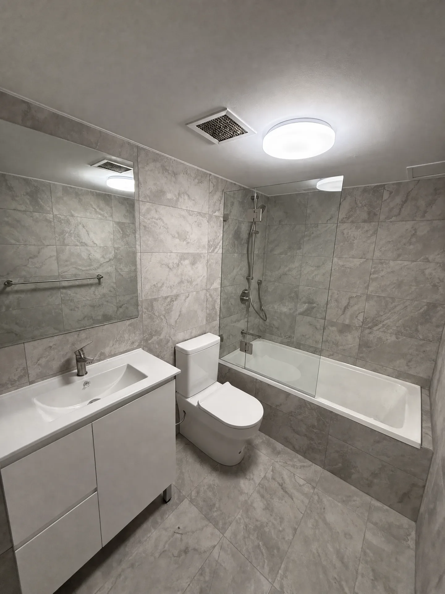 White vanity with wide basin, frameless mirror and shower over the bath