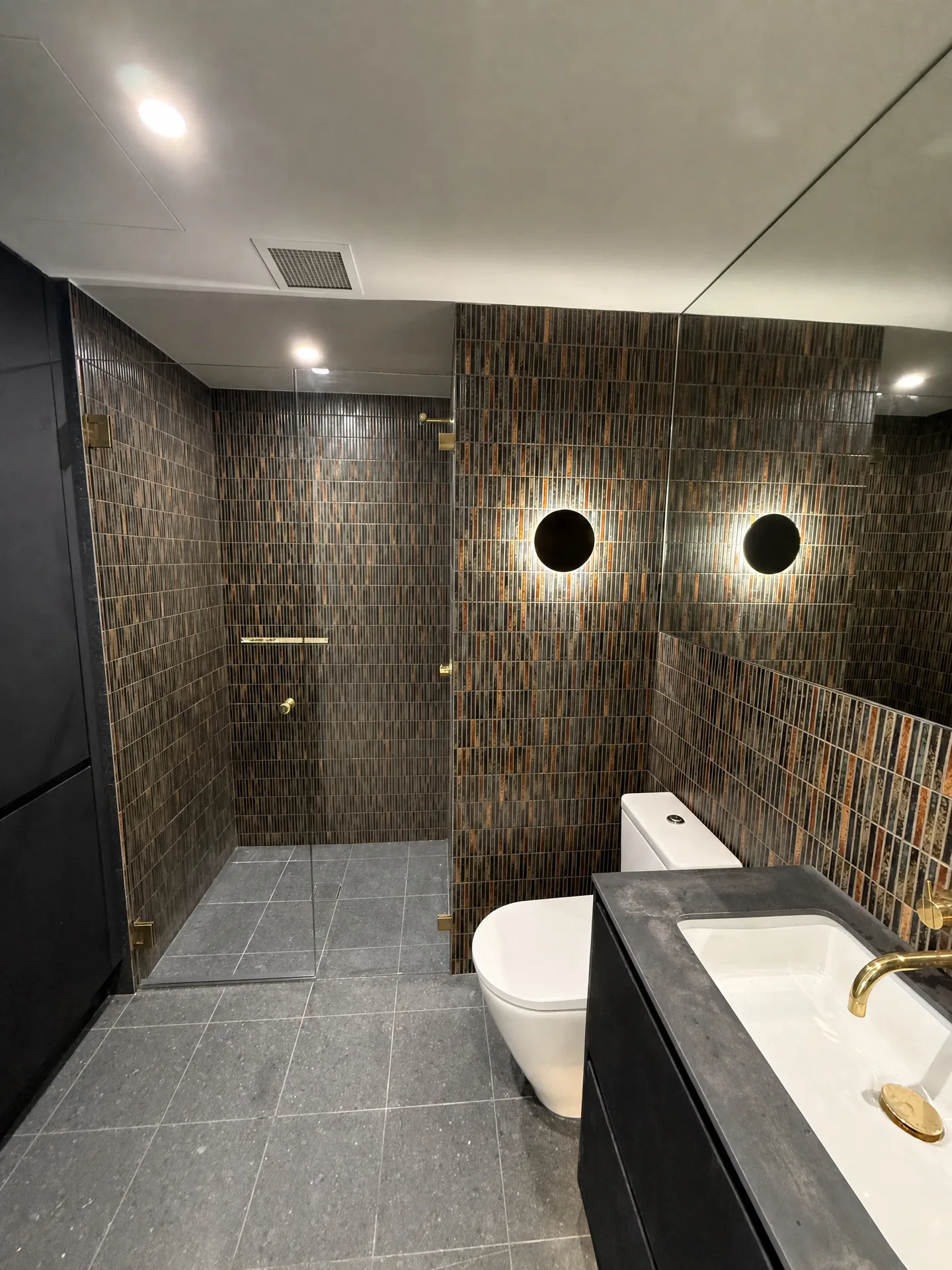 Second bathroom with bronze vertical mosaic walls, a walk-in shower and dark vanity
