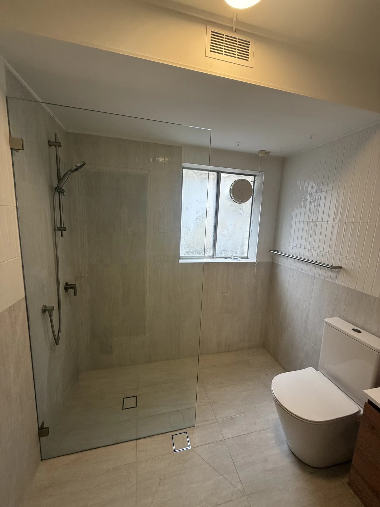 Randwick apartment bathroom with a step-free walk-in shower behind a single fixed frameless glass panel