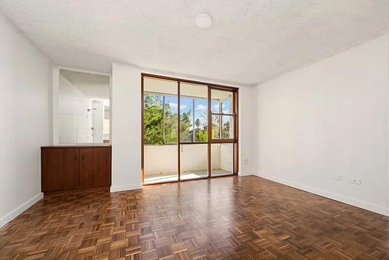 Living room with original parquet flooring and timber-framed sliding doors to a balcony