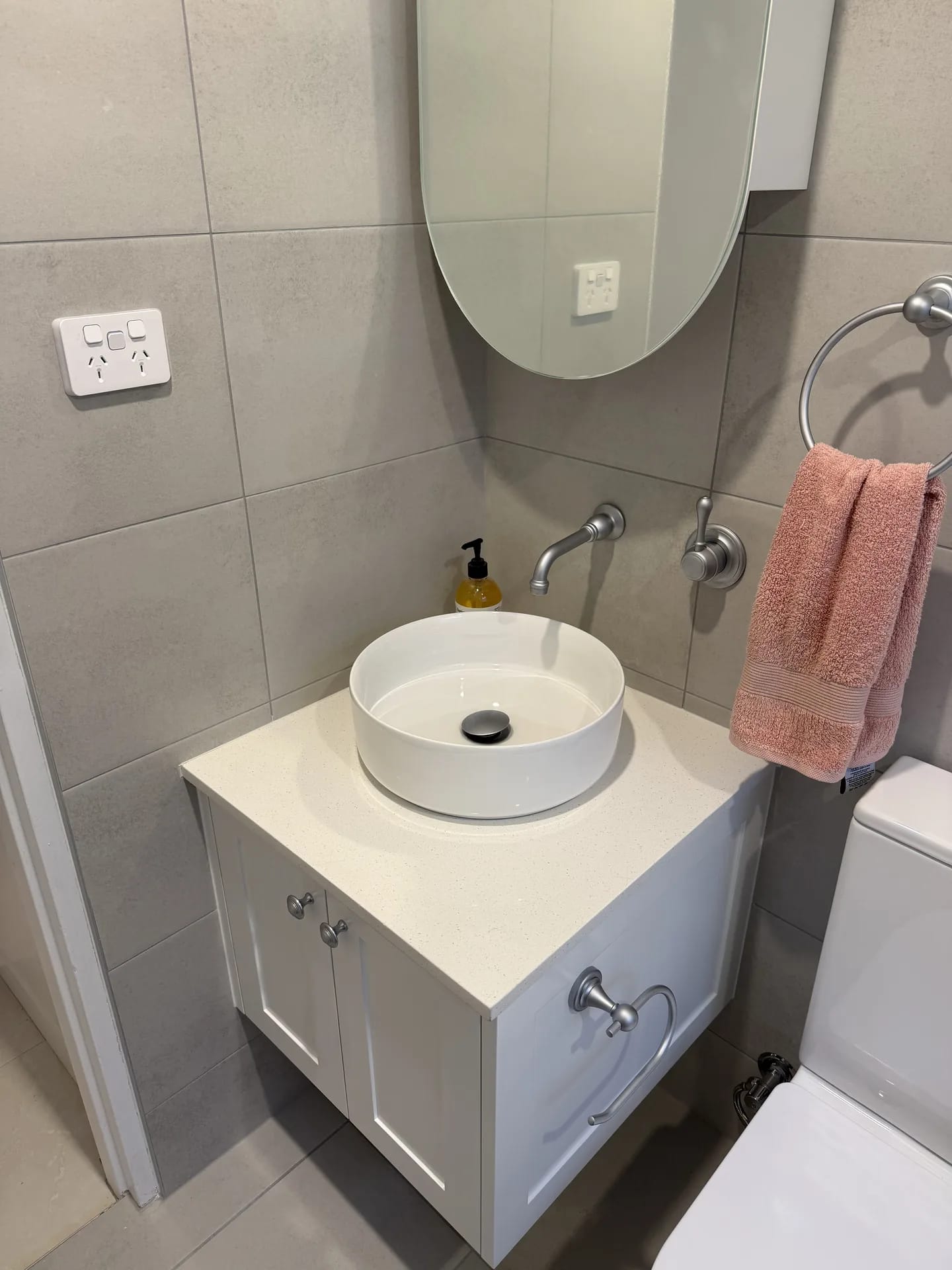 Round vessel basin on a shaker vanity with a wall-mounted brushed nickel spout