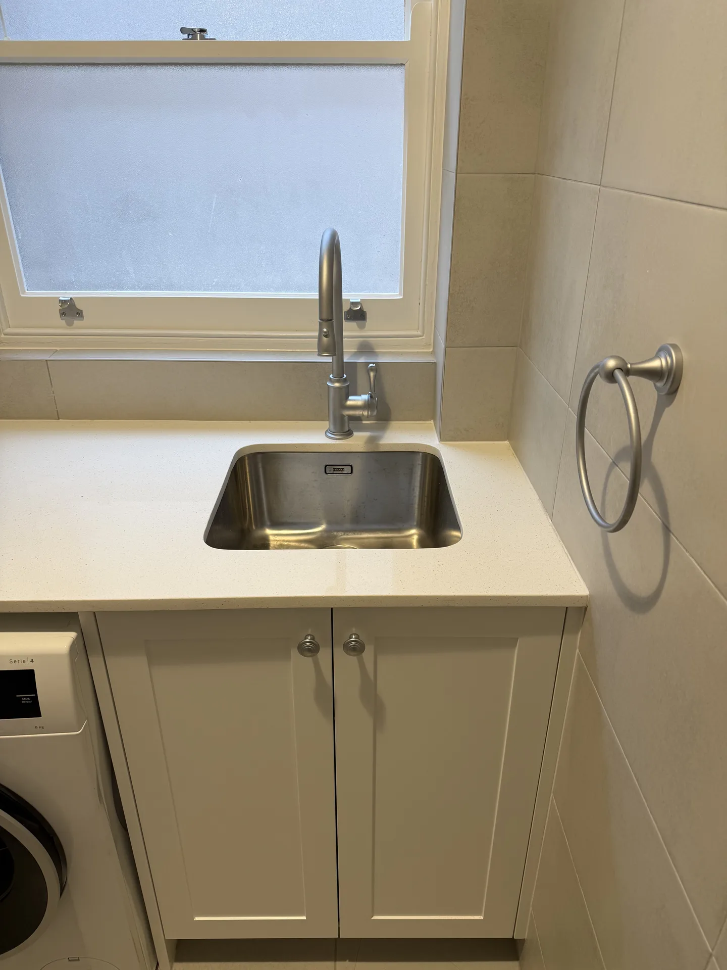 Stainless undermount laundry sink with a gooseneck tap set in a stone-look benchtop