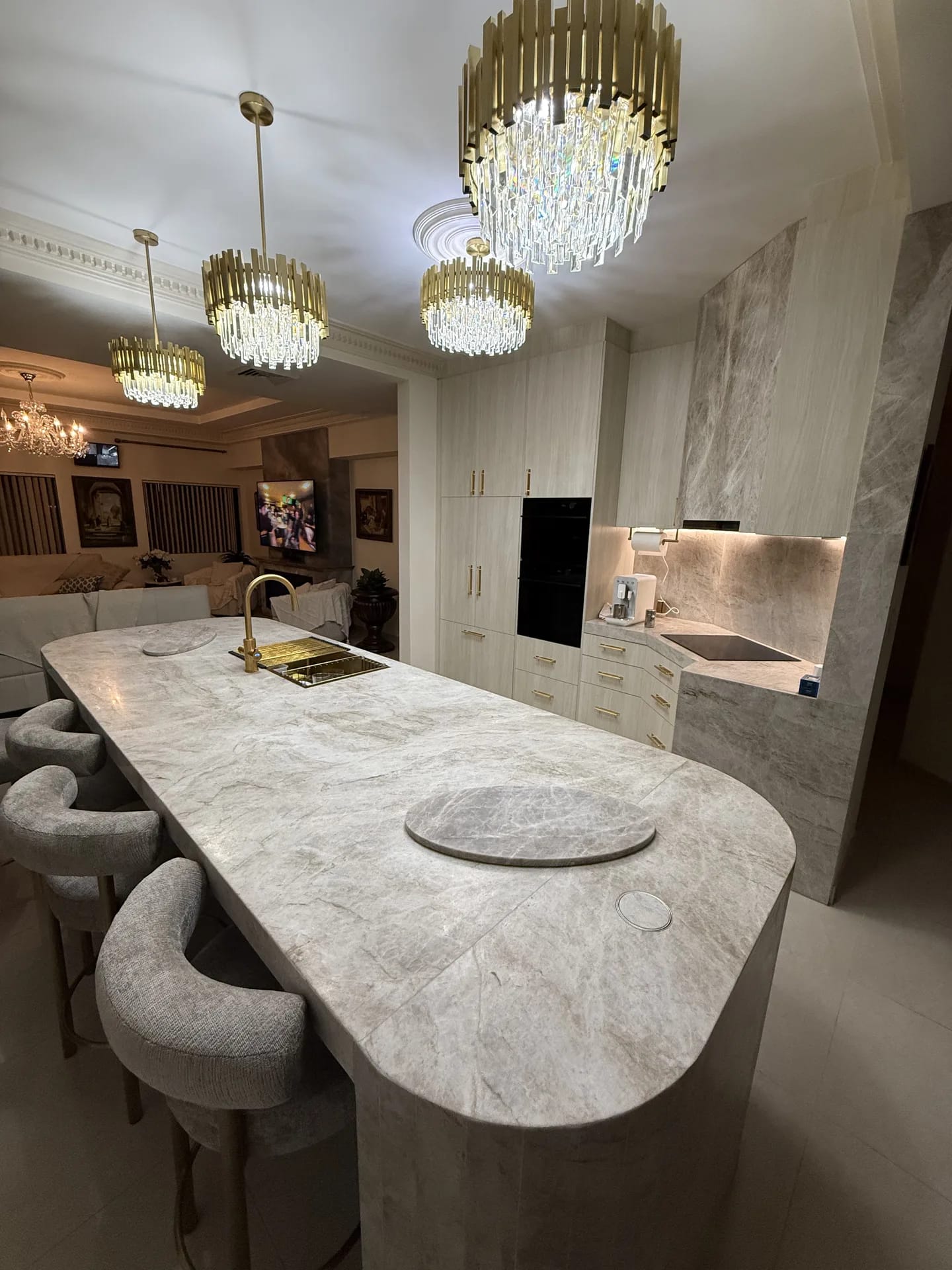 View along the island toward tall cabinetry, integrated ovens and the living room