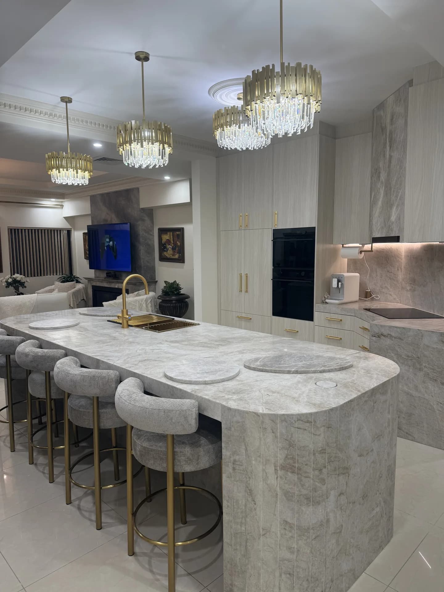 Renovated Vaucluse kitchen with a long curved stone island and brass pendant lights