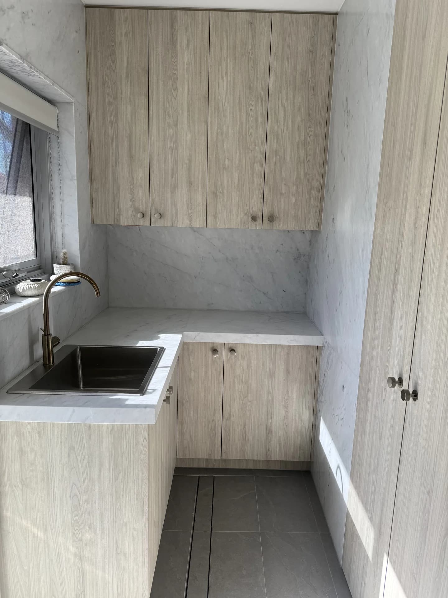 Renovated Vaucluse laundry nook with timber cabinetry, marble benchtop and brass tap