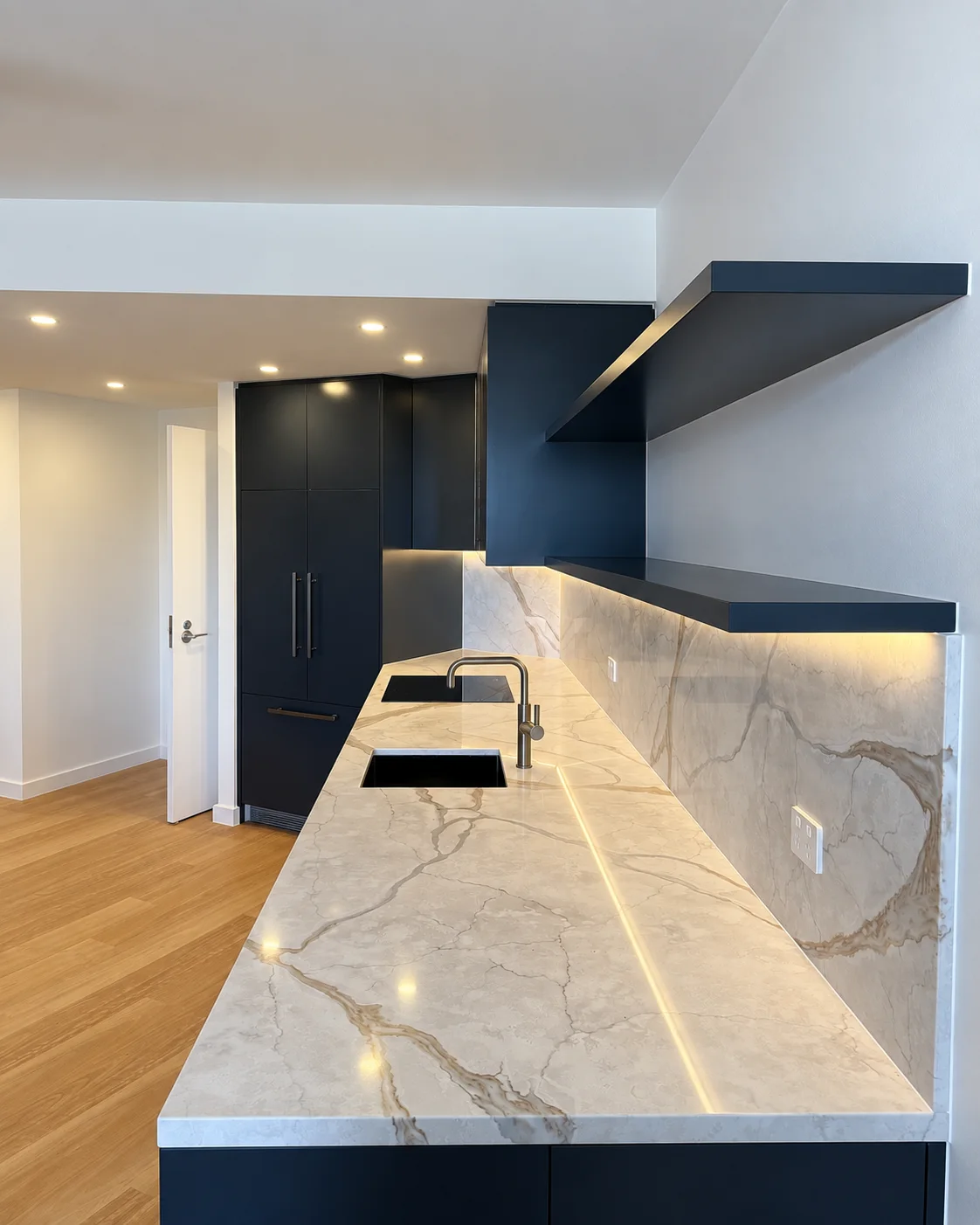 Long kitchen worktop with inset sink, dark blue cupboards and two open shelves