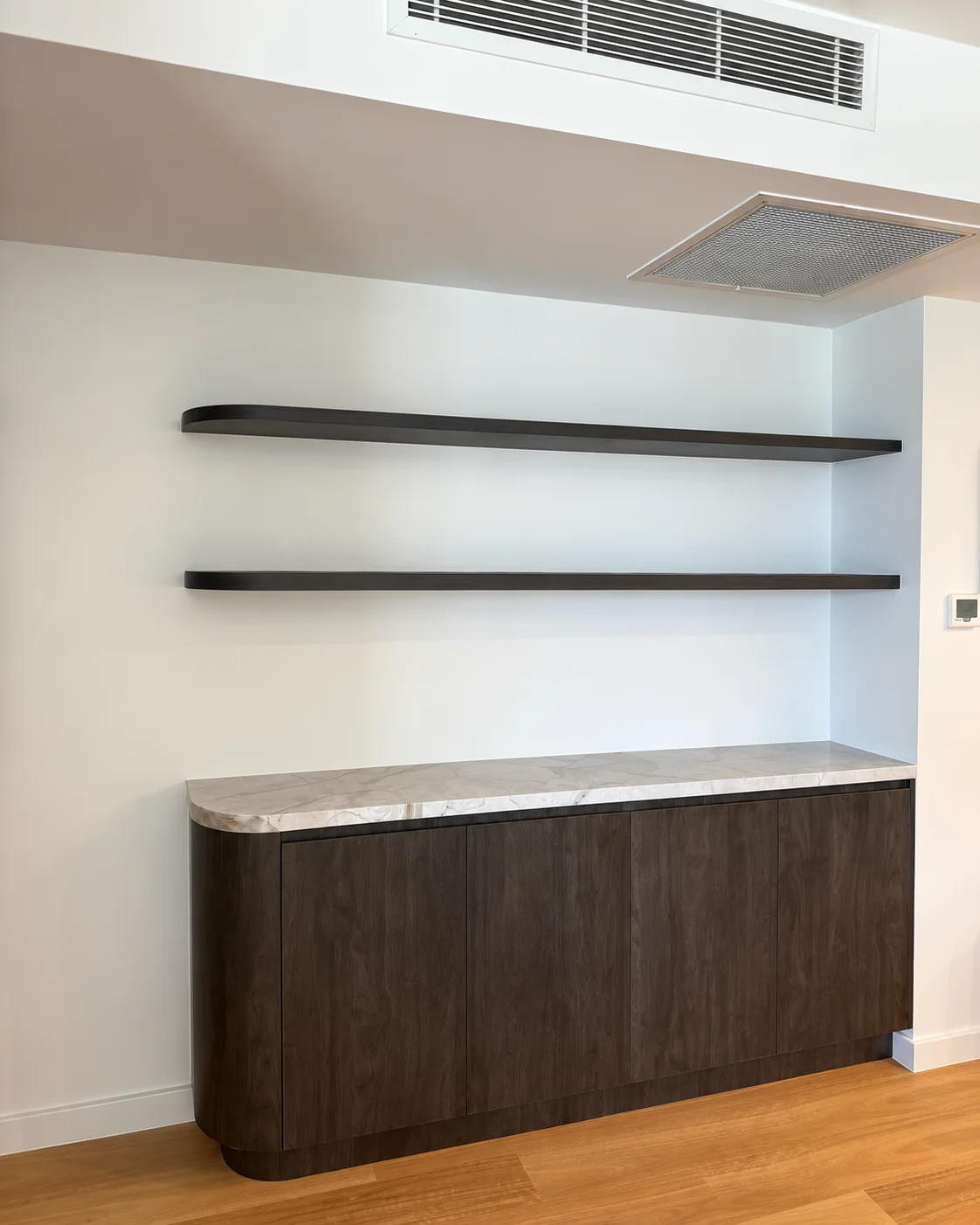 Curved dark timber sideboard with pale veined top and two floating shelves