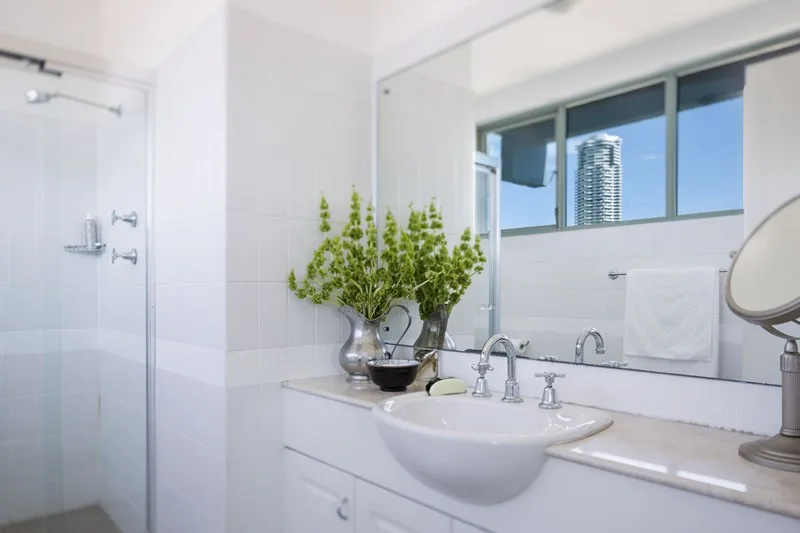 Original bathroom with white square wall tiles, framed shower screen and chrome tapware